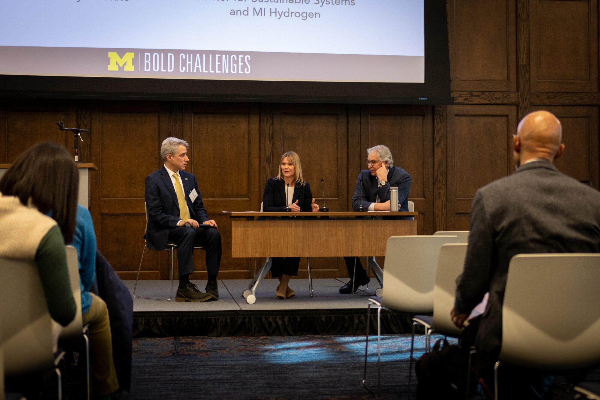 photo of a panel event on a stage in Ruthven Hall, featuring Arthur Lupia, Maggie Allen and Greg Keoleian